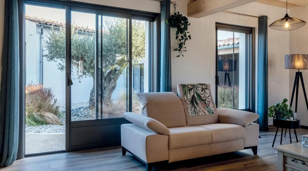 Baie vitrée coulissante en aluminium anthracite ouverte depuis un salon sur un jardin à La Souterraine