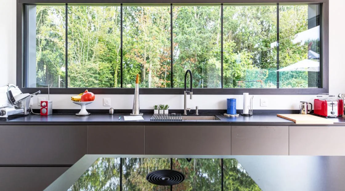 Fenêtre aluminium noir formant un bandeau panoramique au-dessus d'un plan de travail de cuisine à La Souterraine