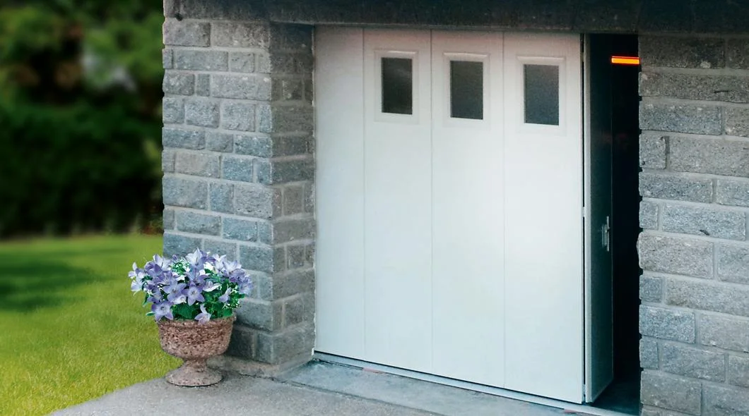 Porte de garage coulissante latérale blanche installée dans un encadrement en pierre à La Souterraine