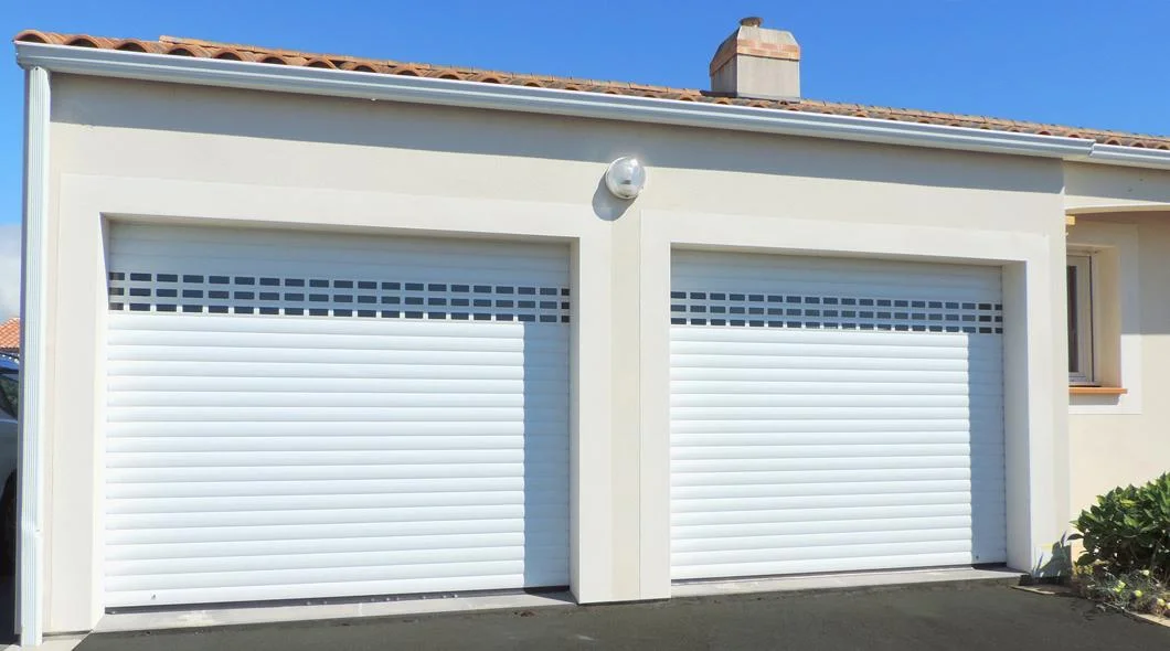 Deux portes de garage enroulables blanches à lames ajourées sur une maison à La Souterraine