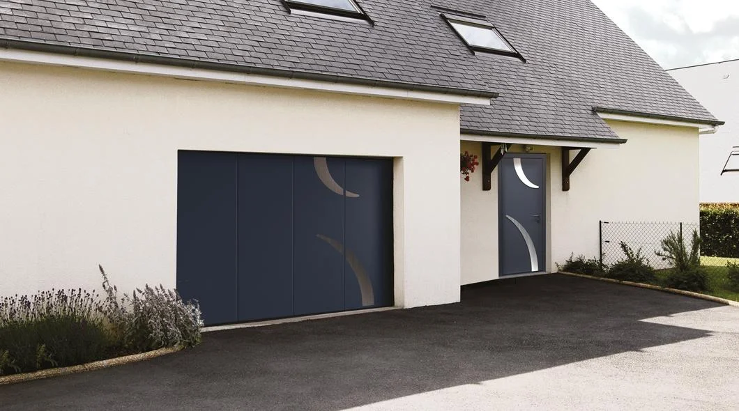 Deux portes de garage sectionnelles anthracite équipées de hublots, sur une maison à enduit clair à La Souterraine