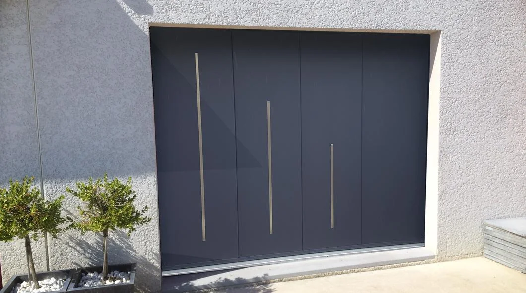 Porte de garage sectionnelle anthracite à rainures verticales inox sur une façade enduite claire à La Souterraine